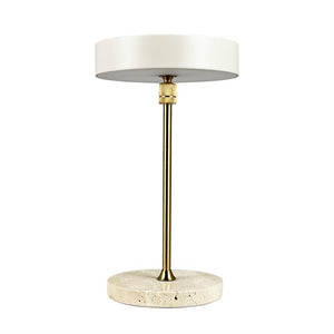 Bordlampe står mod hvid baggrund; rund, mat hvid skærm, slank messingstang og rund travertinfod i lys sten.