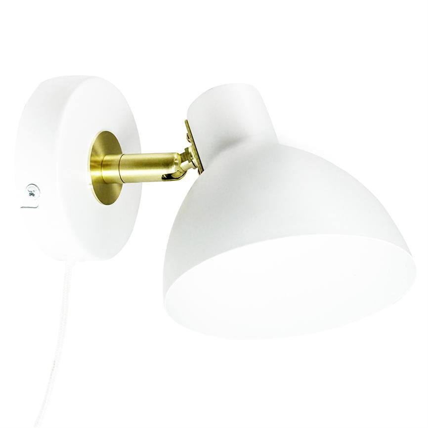 Væglampe vipper nedad på en kort messingled, fastgjort til en rund hvid vægplade; hvid halvkugleskærm og hvid stofledning mod en ensartet hvid baggrund.