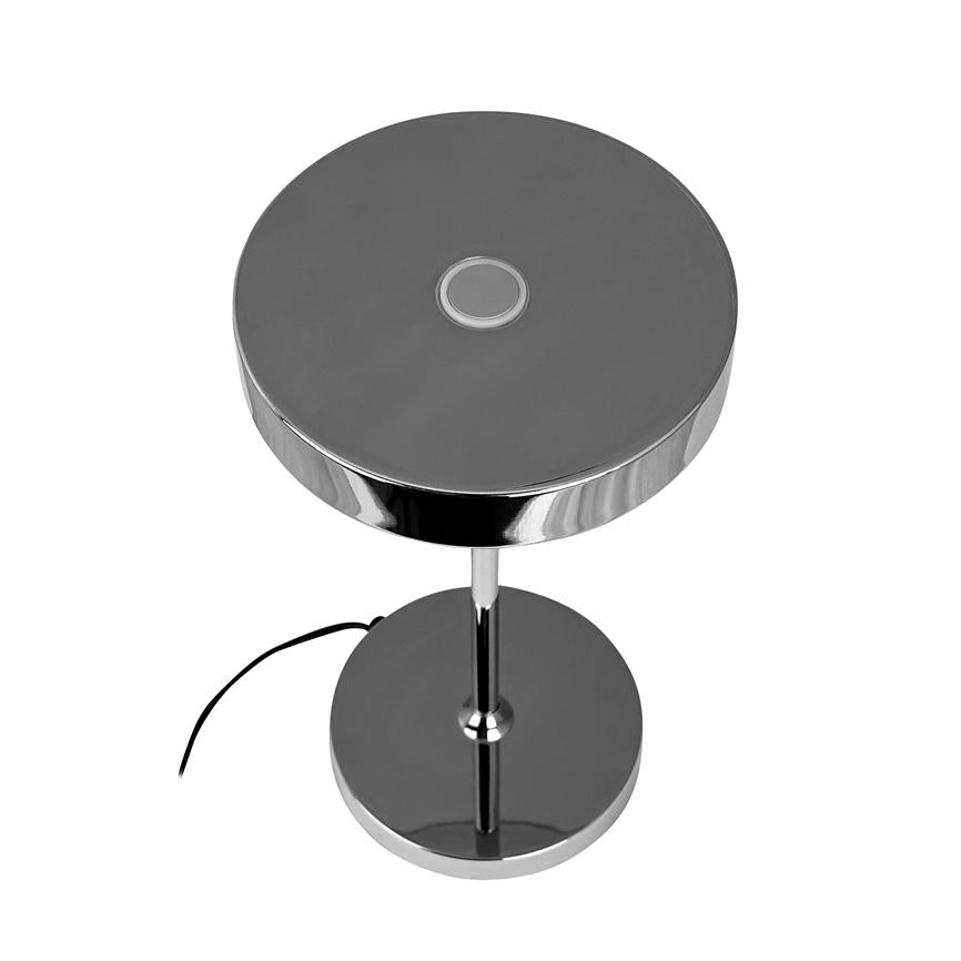Krom bordlampe med rund top og central berøringsknap; står på en slank søjle over en rund fod, ledning løber ud mod hvid, neutral baggrund.