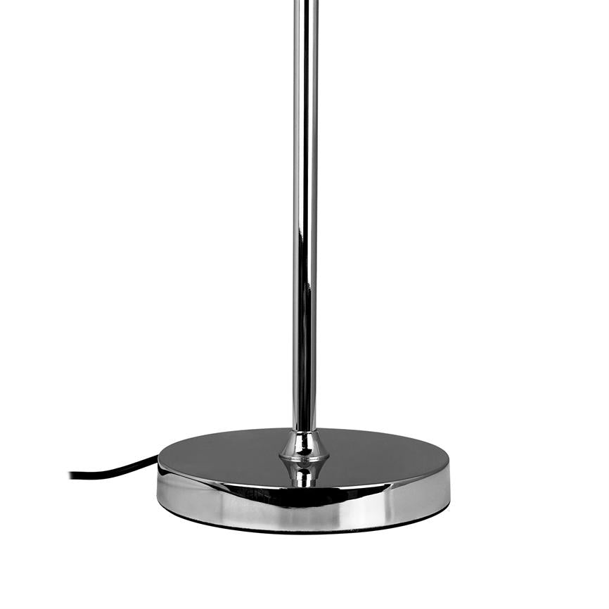 En krom lampefod står oprejst, bærer en slank poleret stang og har en rund, flad metalbase med et sort strømkabel, der løber ud til venstre på hvid baggrund.