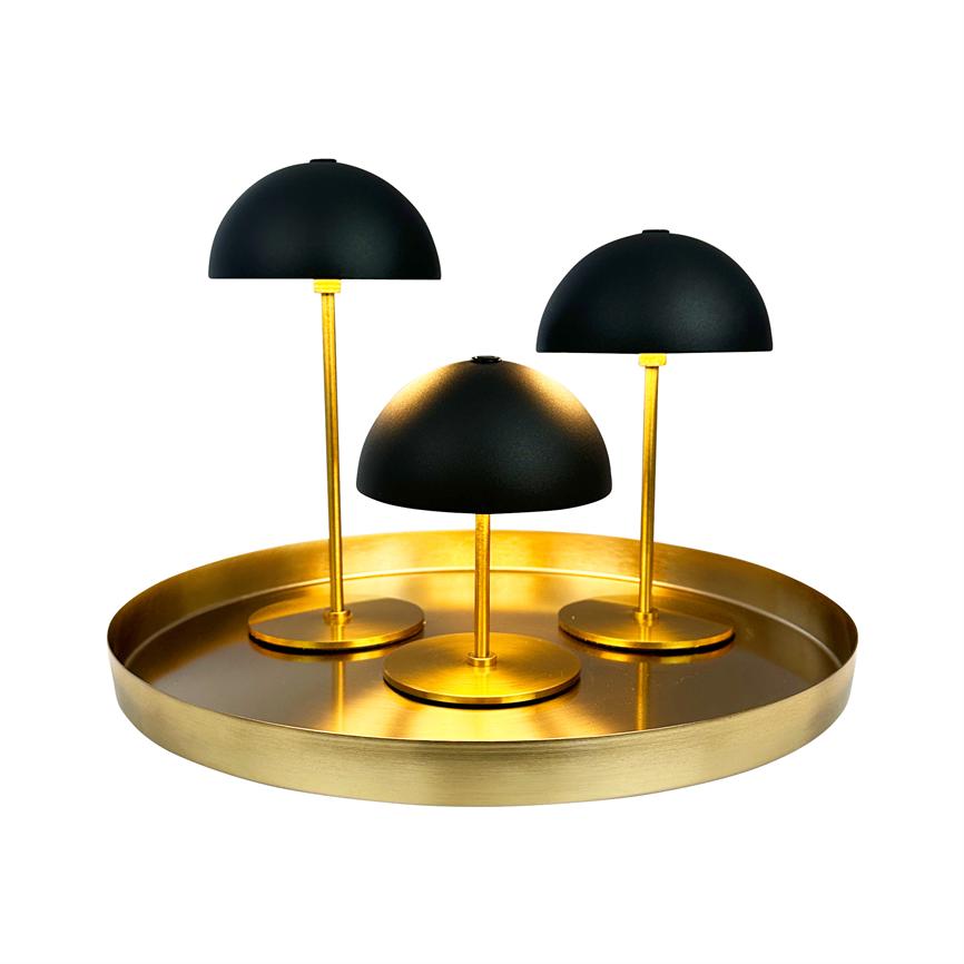 Tre små bordlamper med sorte kupler står på slanke gyldne stænger, placeret på en rund guldfarvet bakke mod en ensartet hvid baggrund.