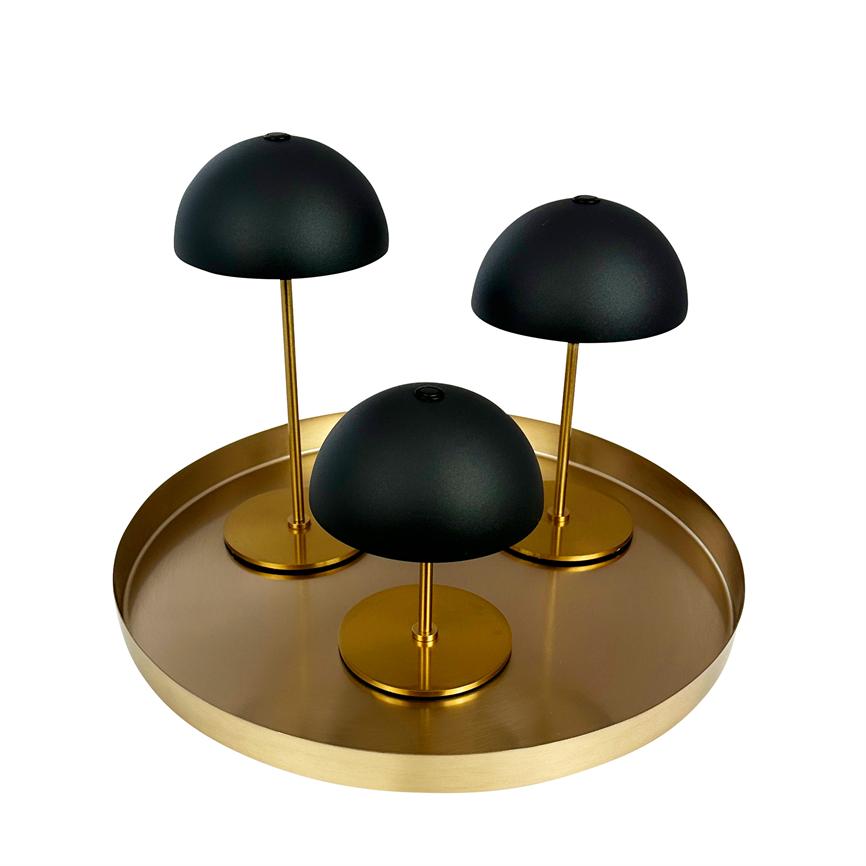 Tre sorte kuppelformede lamper står på slanke, guldstandere i varierende højder og er arrangeret på et rundt, guldfarvet fad mod en hvid baggrund.
