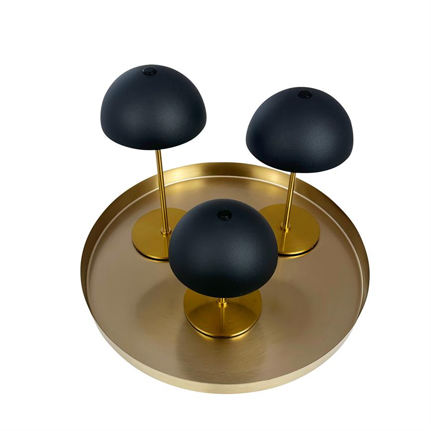 Tre svampeformede matte sorte lamper står på en rund, messingfarvet bakke; to er monteret på høje gyldne stænger og én på kort fod, alt mod hvid baggrund.
