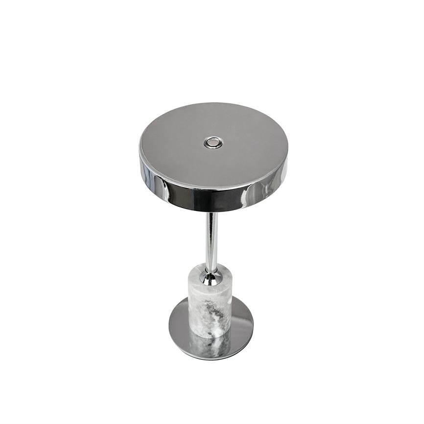 Rund kromplade hviler på en slank kromstang, som står på en hvid marmorcylinder monteret på rund krombase; minimalistisk sidebord/stand mod en ensartet hvid baggrund.