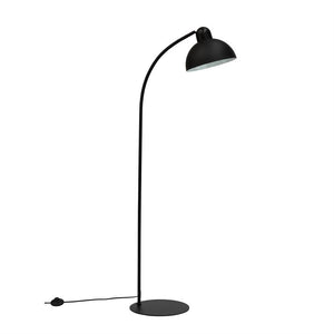 Sort metal gulvlampe med rund fod; en buet stang fører til en halvkugleformet skærm, der peger nedad mod en hvid, ensartet baggrund.