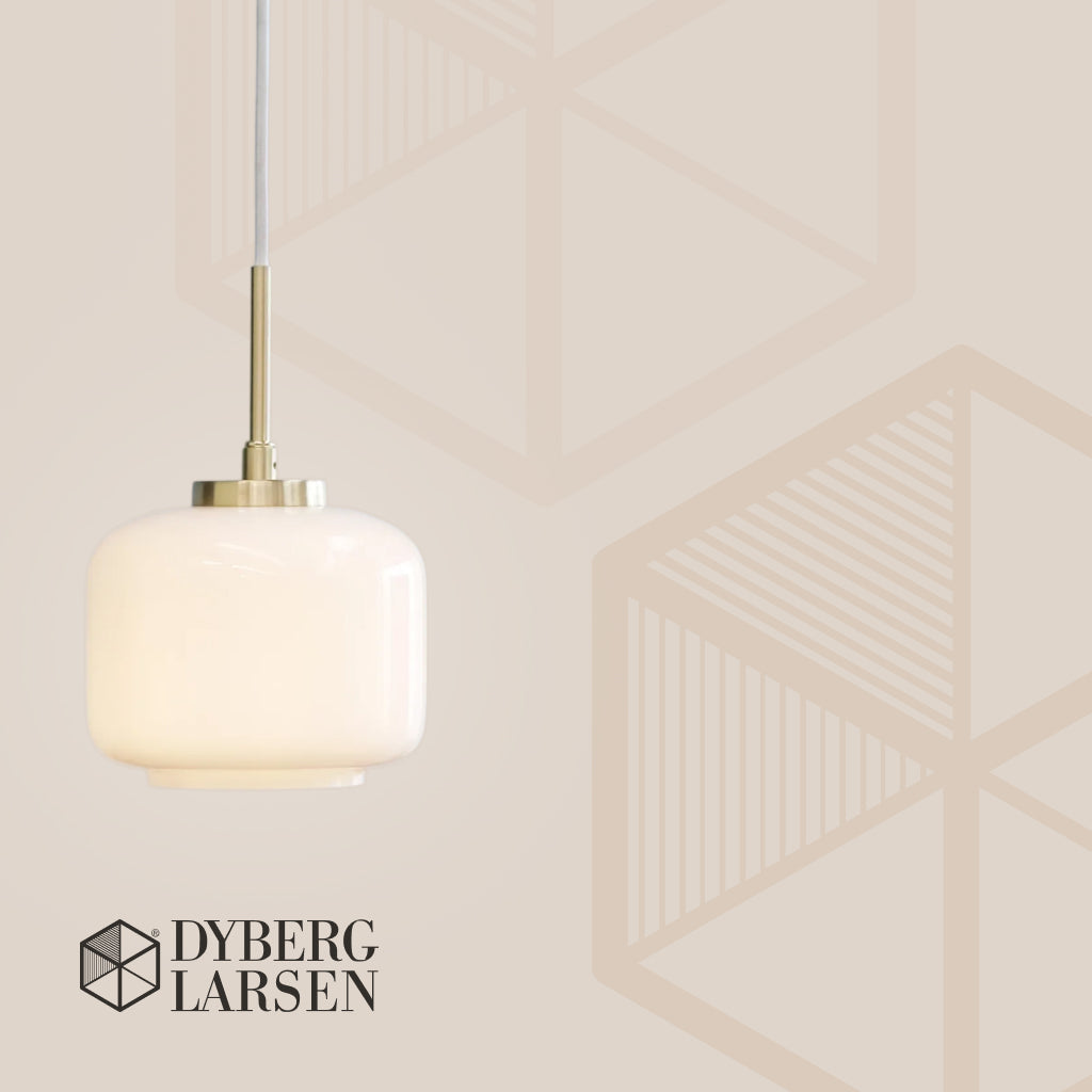En hvid, rund glaspendel hænger i en tynd ledning; varm belysning mod en beige væg med diskret geometrisk mønster. Tekst: "DYBERG LARSEN".